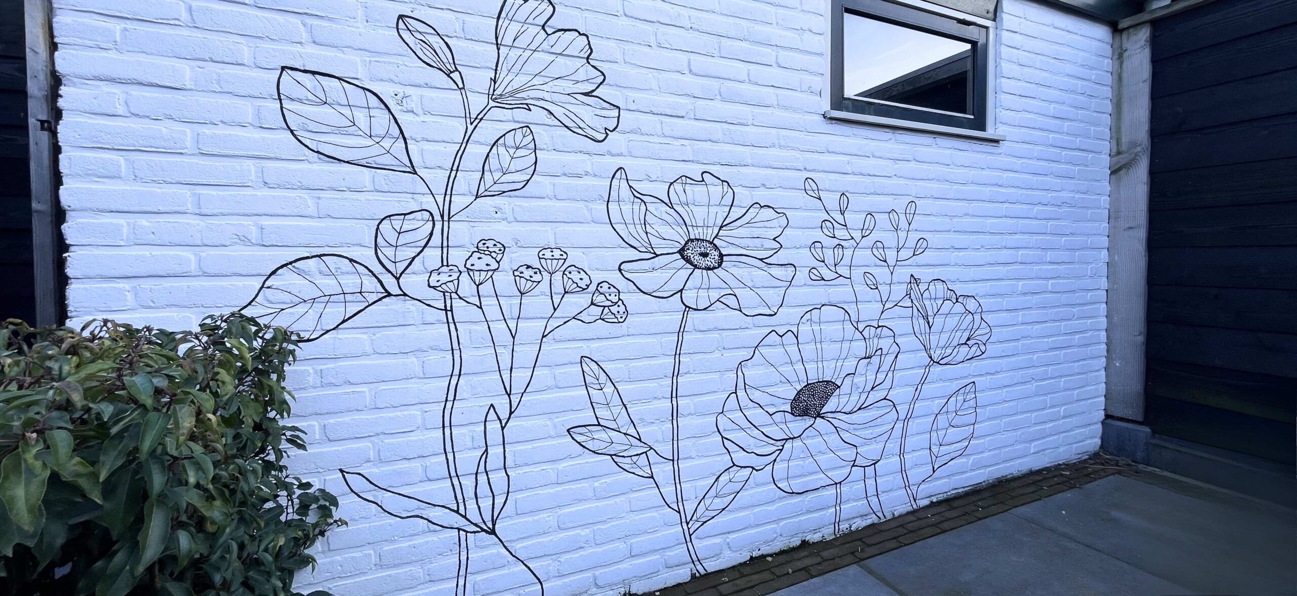 Bakstenen tuinmuur met muurschildering van bloemen