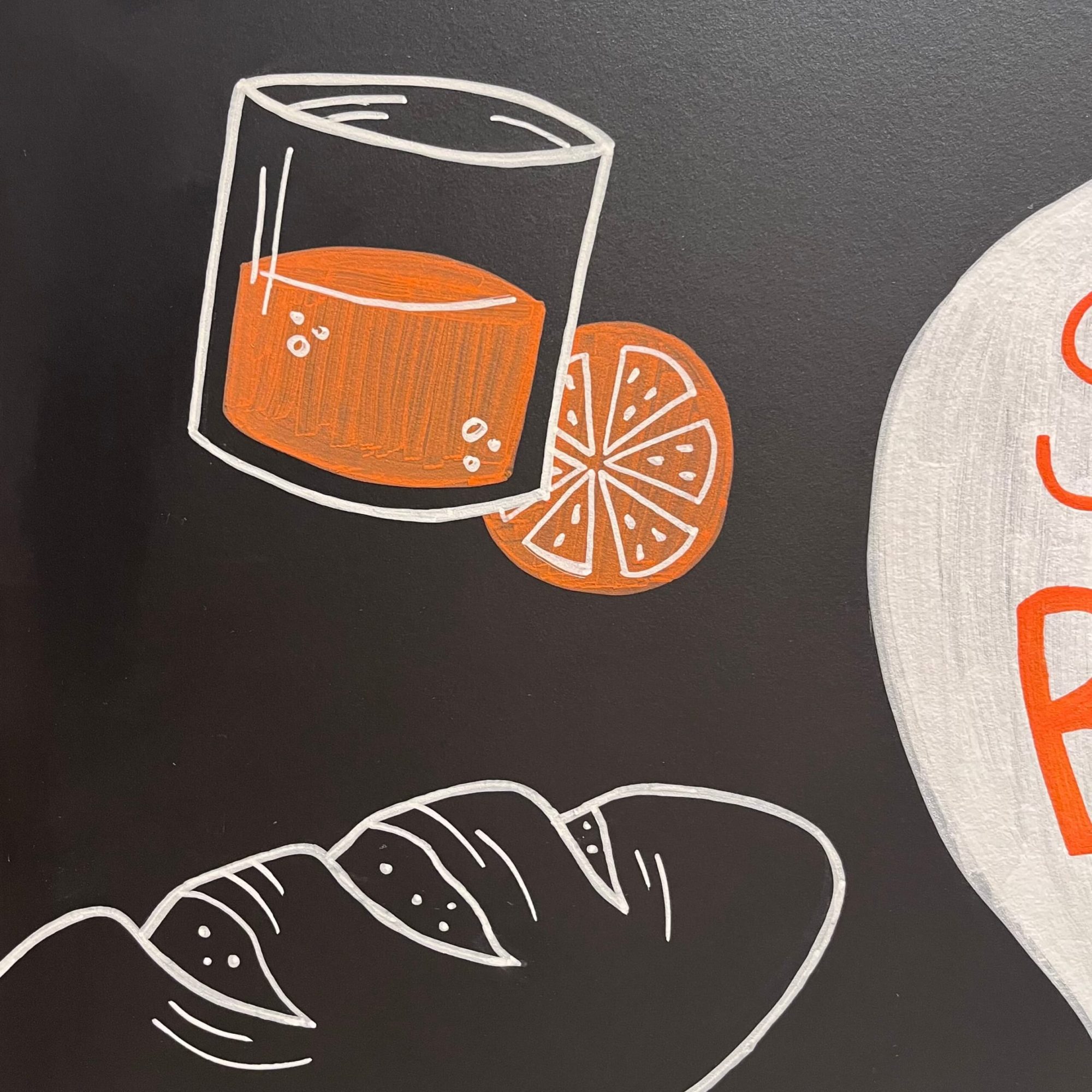 krijtbordtekening van een glas jus d'orange en een brood